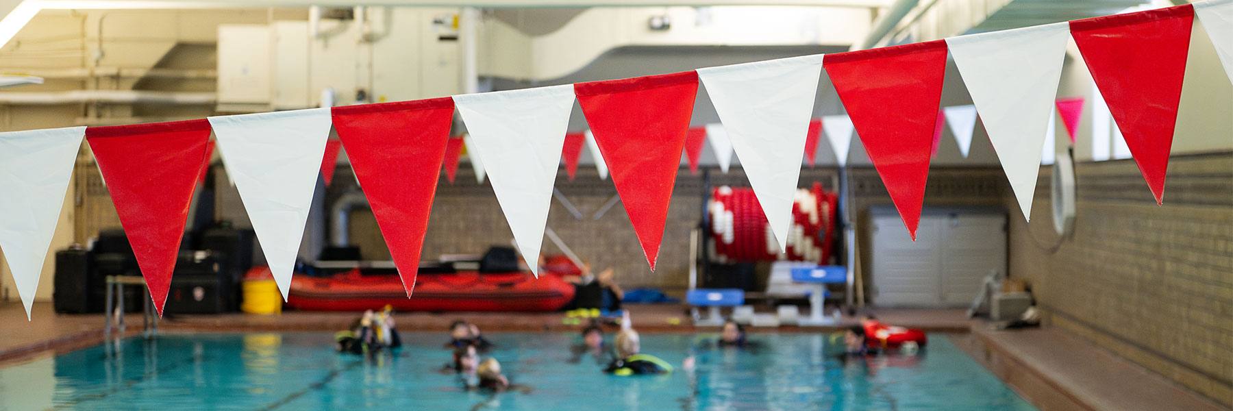 Red and white bunting strung over a pool at Indiana University, where students are taking a scuba class. 