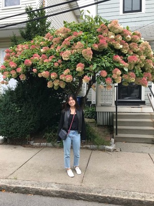 Photo of Jenny Huang in front of a flowering tree.