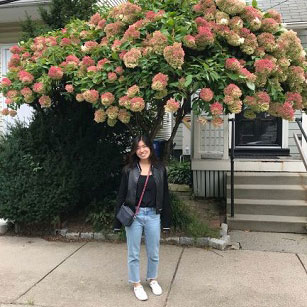 Photo of Jenny Huang in front of a flowering tree.
